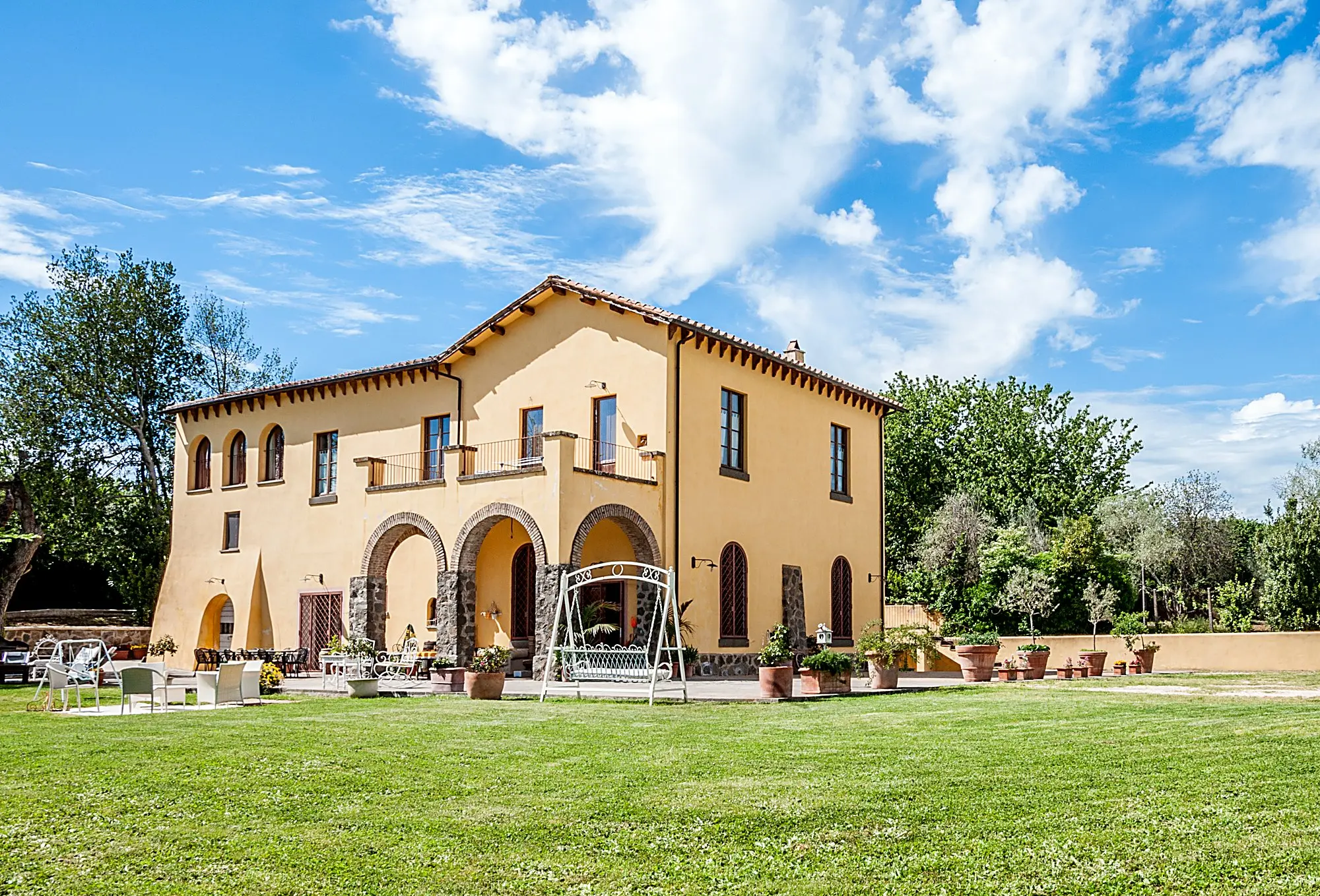 La facciata del Casale con il portico ad archi e l'altalena
