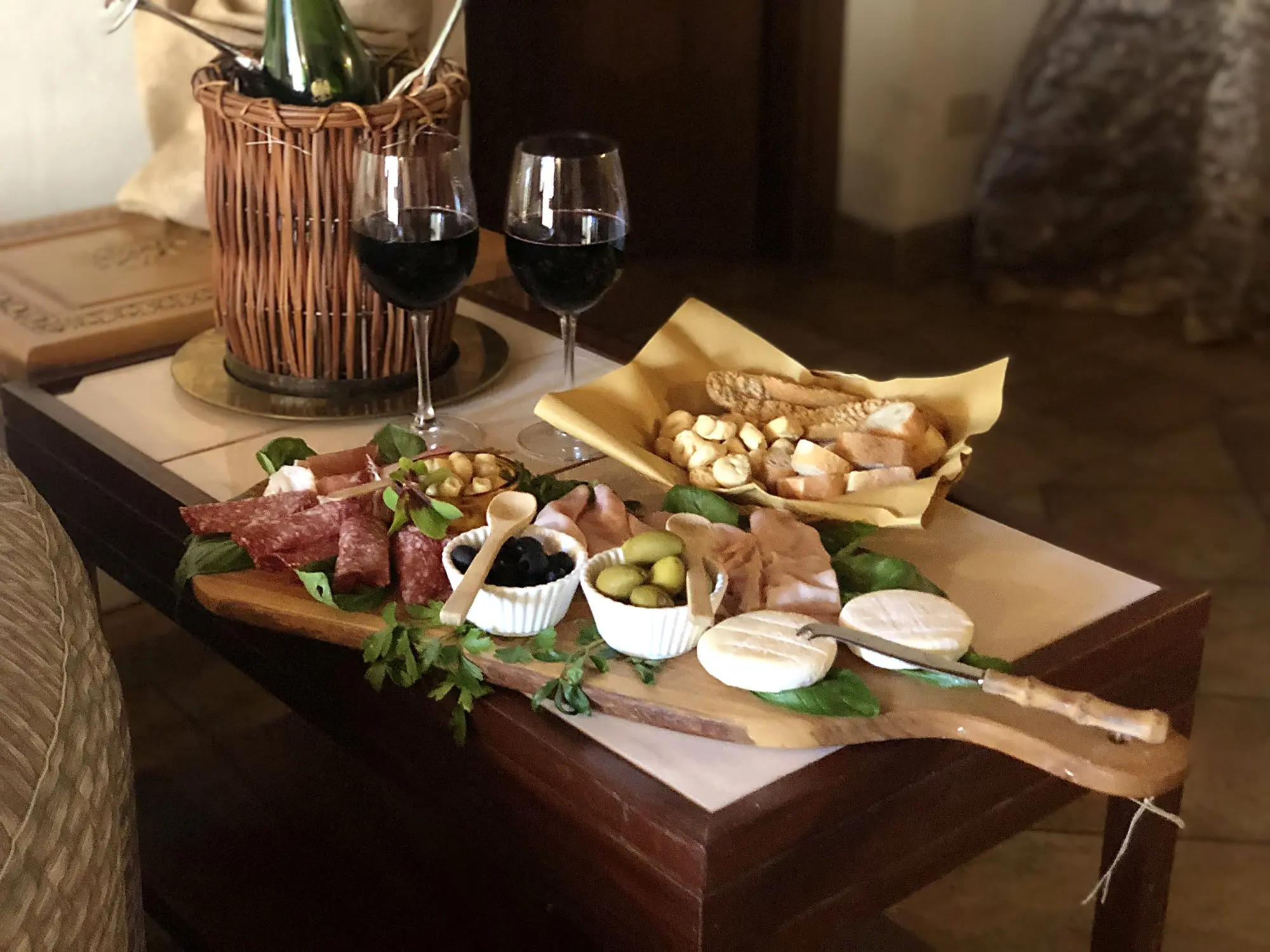 Tagliere di salumi e formaggi con due bicchieri di vino rosso