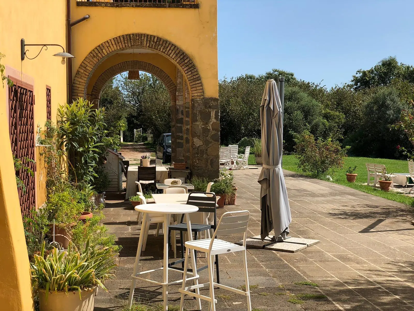 La terrazza lastricata sotto l'arco, con i tavolini